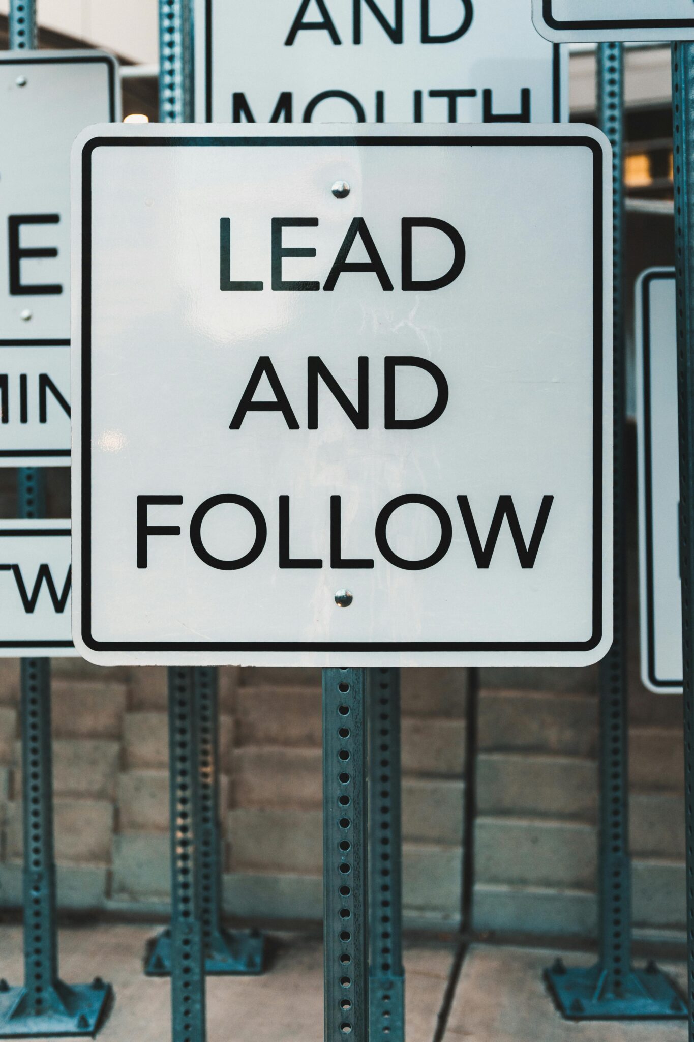 Photo of urban signage displaying 'Lead and Follow', emphasizing guidance and navigation.